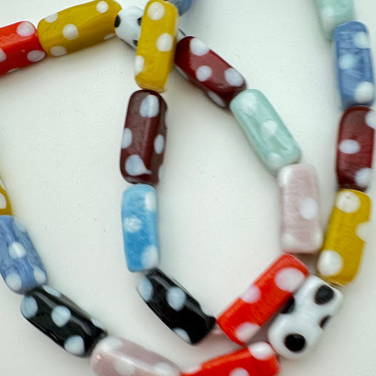 Colorful lampwork beads with polka dot pattern on a white background