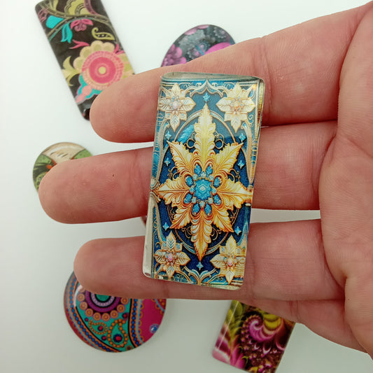 Hand holding a decorative rectangular object with floral patterns on a white background