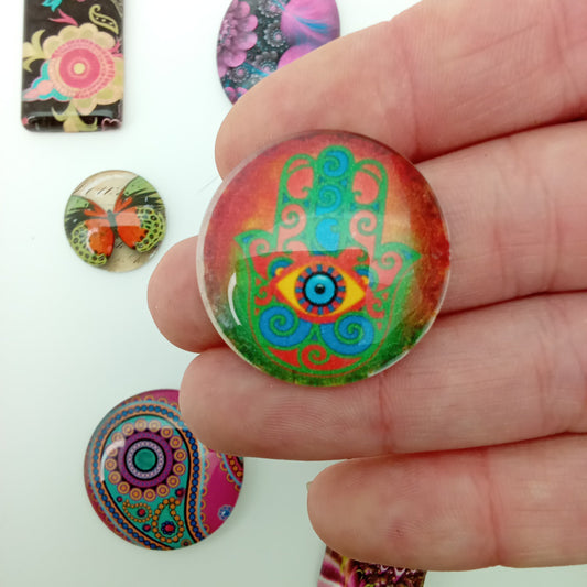 Colorful patterned buttons held by a hand with more buttons in the background.