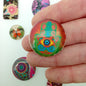 Colorful patterned buttons held by a hand with more buttons in the background.