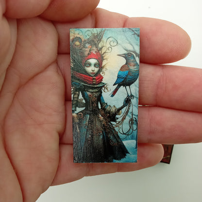 Small rectangular artwork held between fingers against a plain background