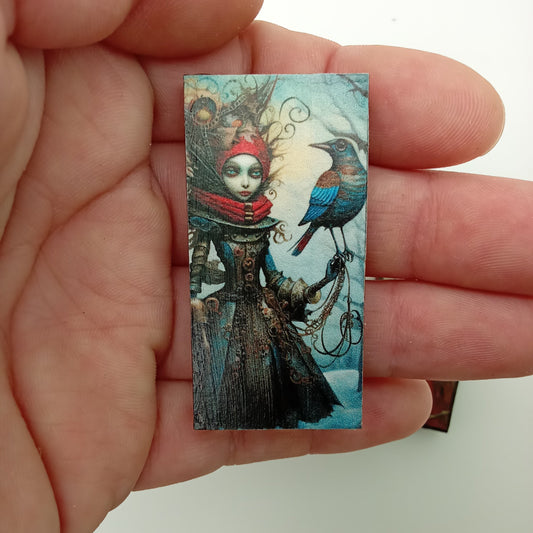 Small rectangular artwork held between fingers against a plain background